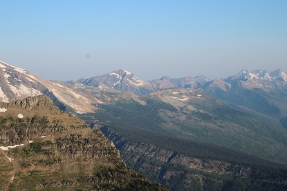 Photo from a mountain crest looking out at other peaks in the distance